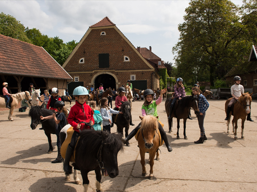 Kinder auf Pferden im Hof